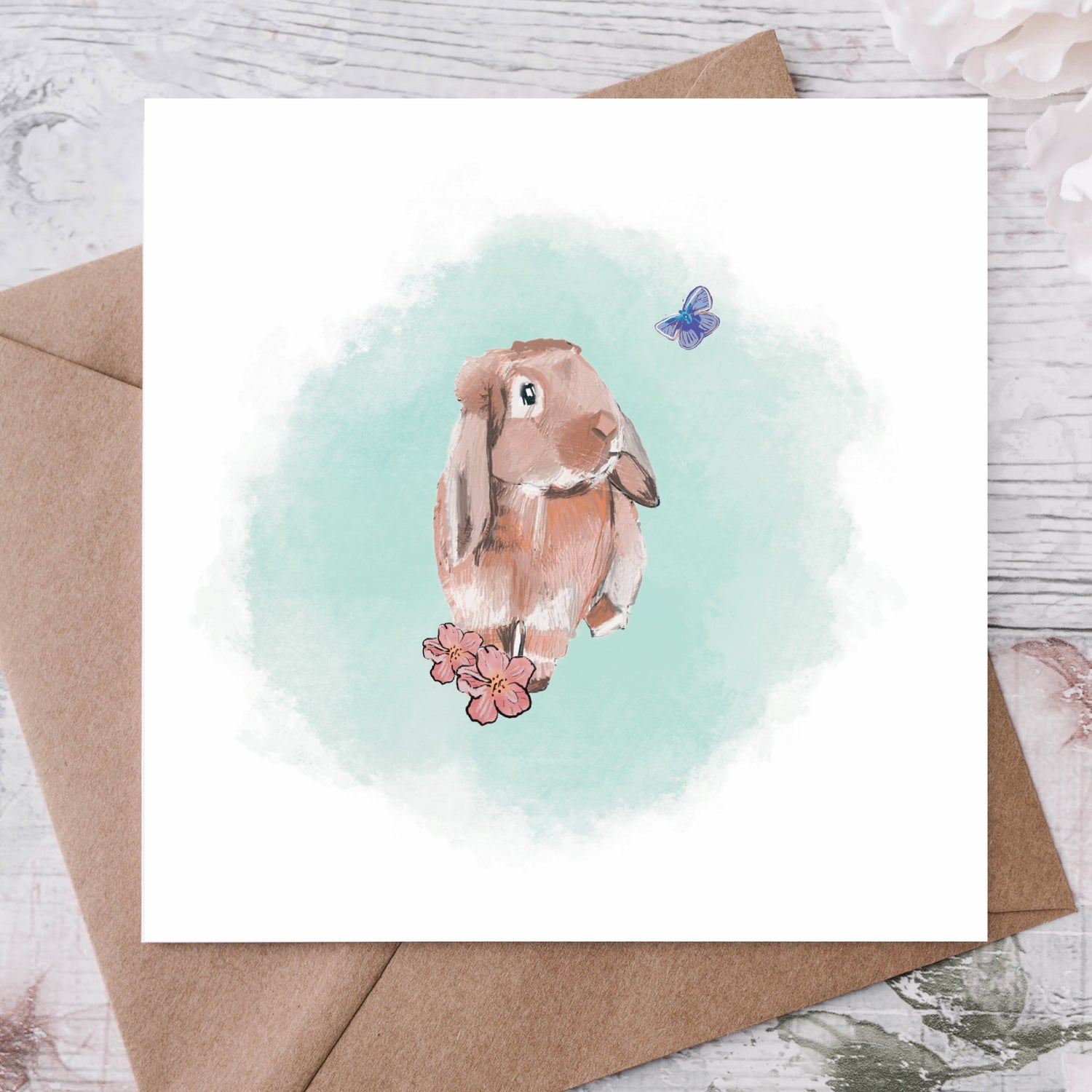 A hand drawn brown rabbit on a green and white square greeting card with a kraft envelope